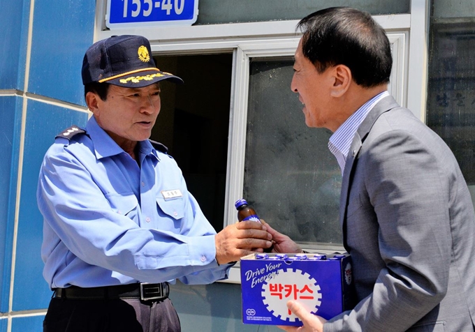 김선재(오른쪽) 배재대 총장이 학교 발전기금을 기탁한 경비원 조동주씨에게 고마운 마음을 담아 음료수를 건네고 있다. 배재대 제공