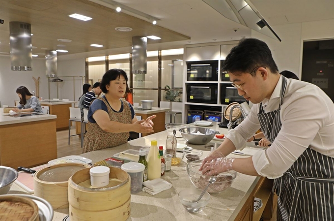 한 남성 직장인이 롯데백화점 문화센터에서 앞치마를 두른 채 요리를 하고 있다. 롯데백화점 제공