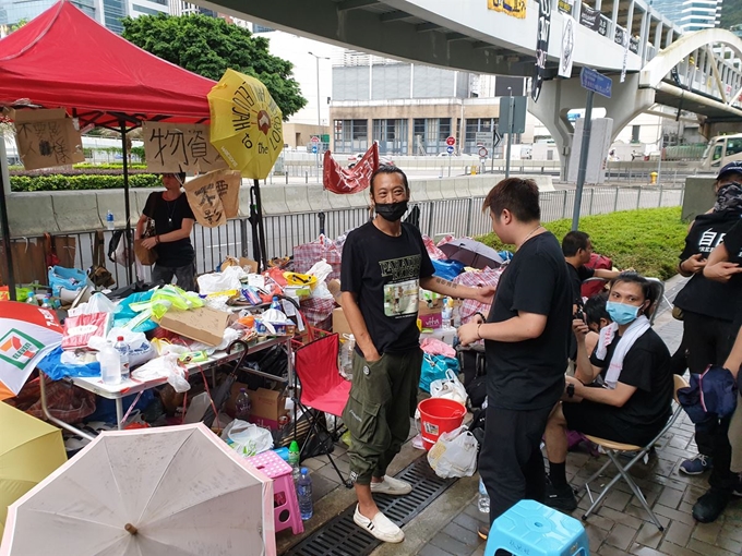 17일 홍콩 도심 입법회 부근에서 시위 참여 시민들에게 물품을 지원하는 자원봉사자들을 만났다. 기자와 한참 이야기하던 노(44ㆍ왼쪽) 씨와 리(27)씨가 저만치에서 지나가는 경찰들을 보더니 갑자기 딴청을 피우면서 시선을 돌리고 있다. 김광수 특파원