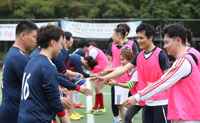 한국얀센과 존슨앤드존슨 계열사의 임직원들이 18일 손기정문화센터 내 축구장에서 열린 '태화샘솟는집 회원들과 함께하는 축구 대회' 경기에 앞서 태화샘솟는집 회원들과 악수를 하고 있다. 한국얀센 제공