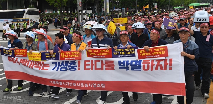 19일 서울개인택시운송사업조합원들이 '타다 아웃, 택시규제 혁신! 전국순례투쟁'에서 광화문 일대를 지나며 택시표시등을 들어올린 채 타다 퇴출 구호를 외치고 있다. 서재훈 기자