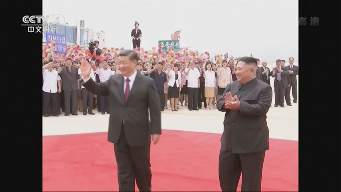 시진핑 중국 국가주석이 20일 평양 순안공항에 도착해 손을 흔드는 사이 김정은 북한 국무위원장은 옆에서 박수를 치고 있다. CCTV 화면 캡처 연합뉴스