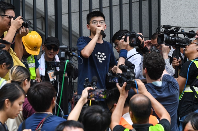 21일 홍콩에서 '범죄인 인도 법안'에 반대하는 검은 옷을 입은 시위자들이 정부청사,입법부 앞 및 주요 도로 점거하며 속속 모여들고 있는 가운데 경찰서 앞에서 2014 우산혁명의 주역인 조슈아 웡이 기자회견을 하고 있다. AFP 연합뉴스