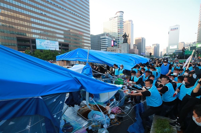 서울시와 용역업체 관계자들이 25일 오전 서울 광화문광장에 설치된 대한애국당의 불법 천막을 철거하고 있다. 연합뉴스