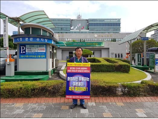 지난 17일 오전 경기도 수원시청 앞에서 홍진선 수원군공항 이전 반대 화성시 범시민대책위원회 상임위원장이 피켓을 목에 걸고 1인 시위를 벌이고 있다. 범시민대책위 제공