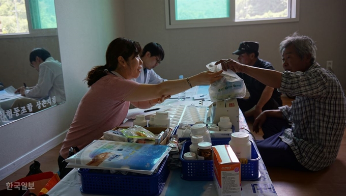 충북 영동군 흥덕리 마을주민이 의료진으로부터 건강상담을 받고 간단한 상비약을 건네 받고 있다.