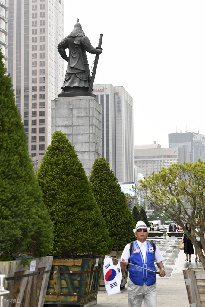 1일 오전 서울 종로구 광화문광장 서울시의 대형화분 사이로 한 노인이 태극기를 들고 걷고 있다. 이한호 기자