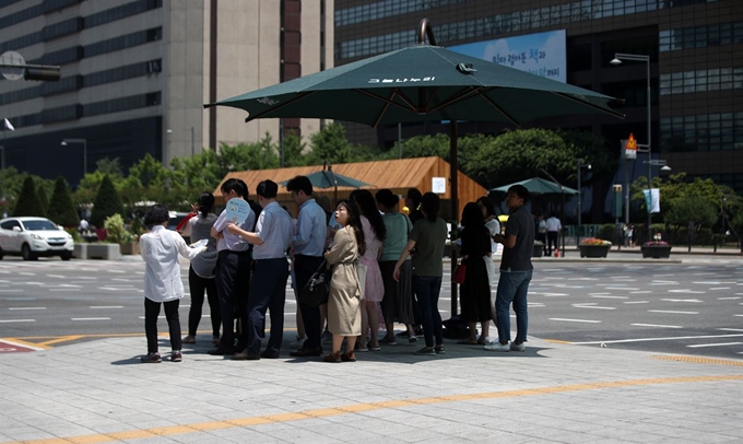 서울 낮 최고 기온이 34도를 기록하며 폭염경보가 발효된 5일 서울 종로구 세종로사거리에 설치된 그늘막 아래에서 시민들이 신호를 기다리고 있다. 뉴시스