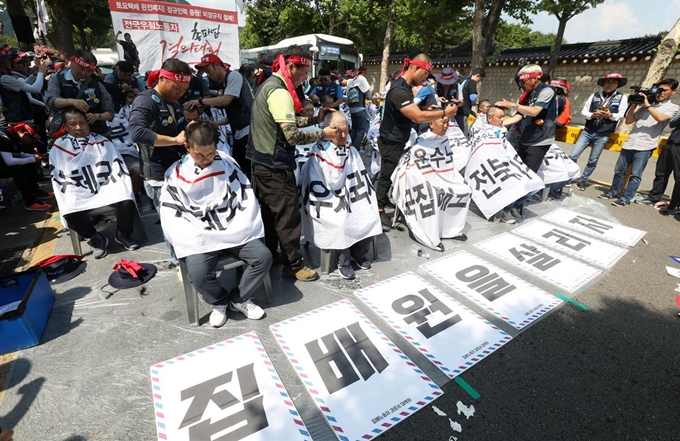 전국집배노동조합원들이 6일 오후 서울 종로구 청와대 사랑채 인근 도로에서 열린 노동조건 개선 촉구 총파업 결의대회에서 삭발식을 하고 있다. 뉴시스