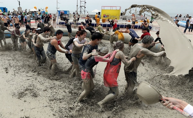 지난해 7월 충남 보령 대천해수욕장 일대에서 개막한 머드축제를 찾은 관광객들이 머드탕에 들어가 게임을 하며 즐거운 시간을 보내고 있다.연합뉴스