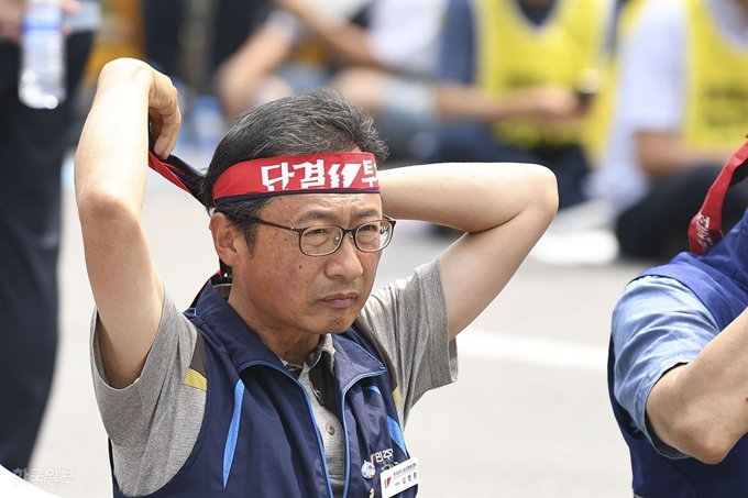 지난 18일 오후 서울 여의도 국회의사당 건너편에서 열린 전 조직 전국 동시 총파업 대회에 참가한 김명환 민주노총 위원장이 머리띠를 조이고 있다. 이한호 기자