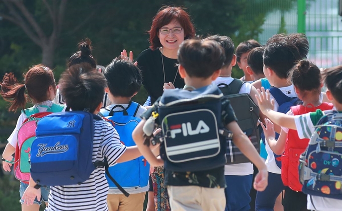 19일 서울 강북구 삼양초등학교에서 2학년 학생들이 방학식을 마친 뒤 교문 앞에서 배웅하는 담임 선생님을 향해 달려가고 있다. 연합뉴스