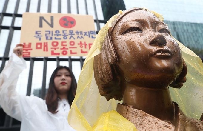 경기 의정부시의 부용고, 송현고, 의정부고 등 6개 고등학교 학생들이 26일 서울 종로구 옛 일본대사관 앞에서 '일본산 제품 불매운동 동참 선언 기자회견'을 했다. 한 학생이 소녀상 뒤로 손 팻말을 들고 있는 모습. 연합뉴스