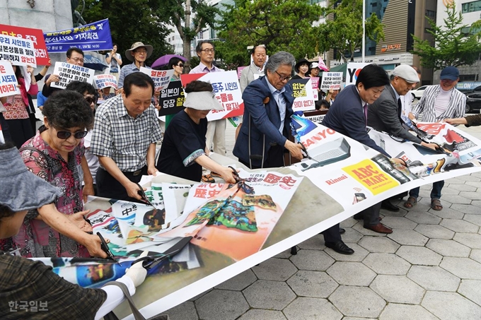 부산시인협회 회원들이 29일 오후 부산 동구 정발 장군 동상 앞에서 일본제품 불매운동 및 항일작품 고취를 위한 기자회견을 열고 일본 서적과 제품이 인쇄된 현수막을 가위로 찢는 퍼포먼스를 벌이고 있다.