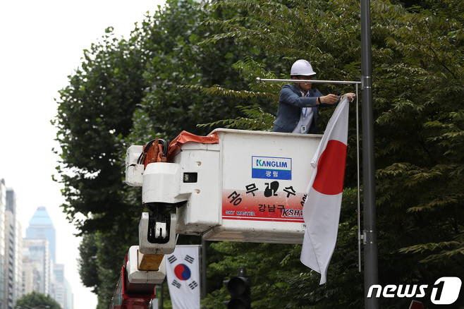 크레인, 특장차 제조업체 광림과 내의류 제조, 유통기업 쌍방울이 독립운동가 후손을 지원하는 사업을 펼치고 있다. 일본 무역보복이 본격화 한 지난 2일 서울 강남구가 광림의 저압선로 보수용 고소작업차를 이용해 테헤란로에 위치한 일장기를 수거하는 모습. 뉴스1 제공