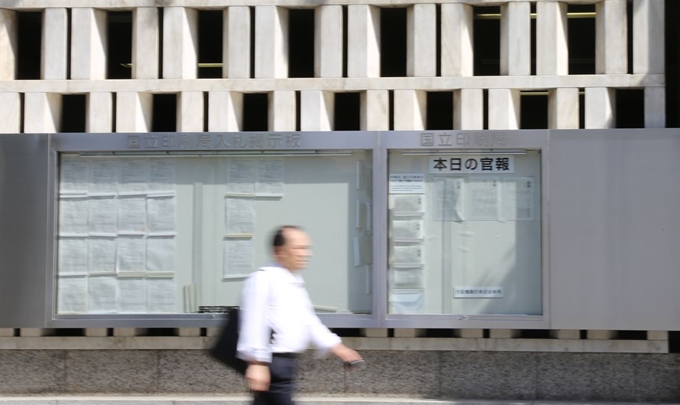 일본 정부가 7일 한국을 수출관리상 일반포괄허가 대상인 화이트리스트에서 제외하는 내용의 수출무역관리령 개정안을 공포한 가운데, 도쿄 국립인쇄국 벽면에 내걸린 관보 앞을 한 시민이 지나가고 있다. 도쿄=연합뉴스