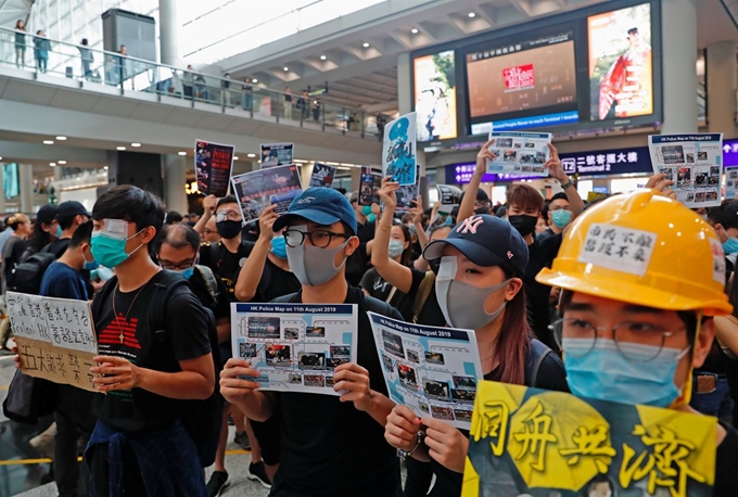 12일 홍콩 국제공항에서 ‘범죄인 인도법안(송환법)’에 반대하는 시위대가 한쪽 눈에 거즈를 붙이고 마스크를 쓴 채 공항을 오가는 관광객들을 상대로 정부 비판 시위를 하고 있다. 전날 홍콩 경찰이 쏜 콩주머니 탄환에 한 여성 시위 참가자가 눈을 맞고 실명 위기에 처한 데 대해 항의를 표하고 있는 것이다. 홍콩=로이터 연합뉴스