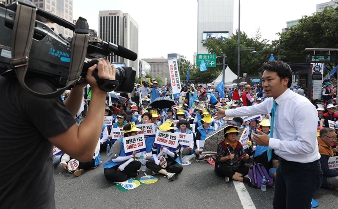 한국자유총연맹 관계자들이 13일 서울 종로구 동화면세점 앞에서’자유무역 파괴·경제침략 아베 정권 규탄대회’를 하는 가운데 일본 TV아사히에서 이를 취재하고 있다. 뉴시스