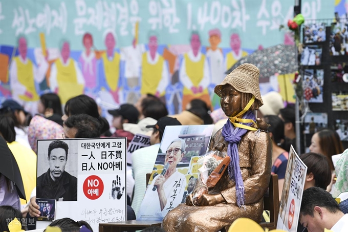 광복절을 하루 앞둔 14일 오후 서울 종로구 옛 일본대사관 앞에서 제1,400회 일본군 성노예제 문제해결을 위한 정기 수요시위 참가자들이 소녀상 주위로 ‘NO 아베’ 등의 문구를 적은 팻말을 들고 있다. 이한호 기자