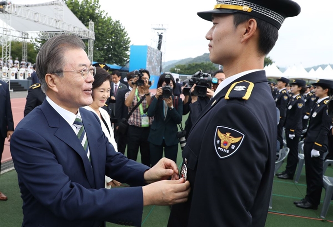 문재인 대통령이 23일 오전 충북 충주 중앙경찰학교에서 제296기 졸업생들에게 경찰관을 상징하는 흉장 수여 후 격려하고 있다. 연합뉴스