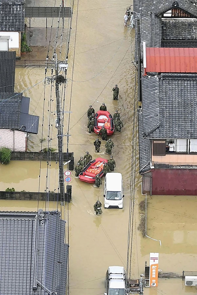 일본 규슈에 기록적 폭우가 쏟아져 후쿠오카현, 사가현 등에 '호우 특별 경보' 발령되고 85만명이 긴급 대피한 가운데 28일(현지시간) 사가현 타케오에서 구조작업 중인 일본 자위대 소속 군인들이 보트를 끌고 침수된 거리를 이동하고 있다. 교도뉴스,AP 연합뉴스