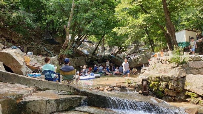 경기 남양주시 별내면 청학리 수락산 계곡에서 피서객들이 물가 자리에 앉아 여유롭게 휴식을 취하고 있다. 이 계곡은 물가 좌대 등의 불법 시설물이 철거된 뒤 자연계곡의 모습을 되찾았다. 남양주시 제공