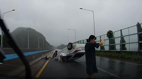 지난 7일 부산 기장군에서 전복된 차량에서 부부를 비롯한 소방관 3명이 사고 차량의 부상자를 구조하는 모습. 부산소방재난본부 제공