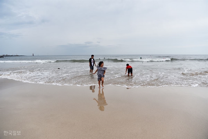 제주 애월읍 곽지해수욕장에서 한 가족이 해변으로 얇게 퍼지는 파도를 즐기고 있다. 제주=최흥수 기자