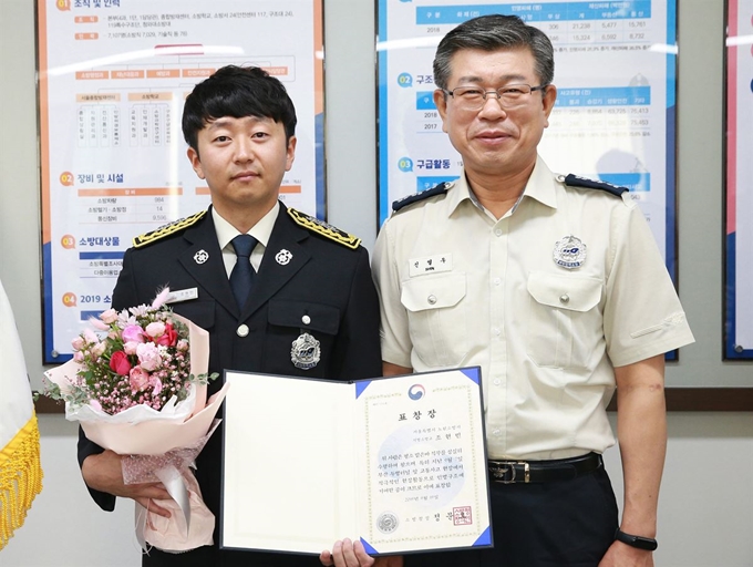 휴무일 전복된 차량에서 인명을 구한 조현민(왼쪽) 서울 노원소방서 소방교가 17일 신열우 서울소방재난본부장으로부터 소방청장 표창장을 받고 기념 촬영을 하고 있다. 서울소방재난본부 제공