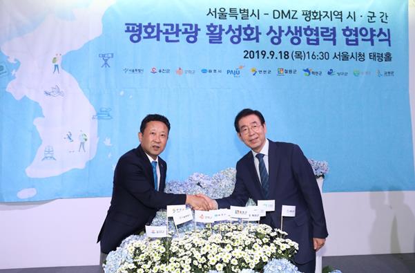 장정민 인천 옹진군수와 박원순 서울시장이 지난 18일 서울시청 태평홀에서 DMZ 평화관광 활성화 협약을 체결한 뒤 악수를 하고 하고 있다. 옹진군 제공