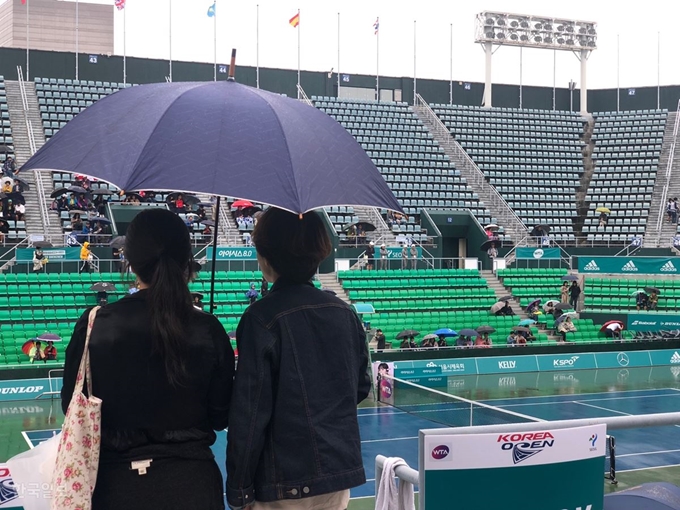 WTA 투어 코리아오픈 단복식 결승전이 열리기로 한 22일 서울 송파구 올림픽공원 테니스경기장에서 관중들이 우산을 쓴 채 텅 빈 경기장을 바라보고 있다. 이승엽 기자