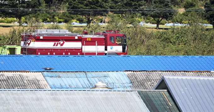 [저작권 한국일보] 경기 파주시 적성면의 한 농가에서 국내 네 번째 아프리카 돼지 열병(ASF) 확진 판정이 나온 24일 오전 발병 축사 지붕 뒤로 소방차가 지나가고 있다. 이한호 기자