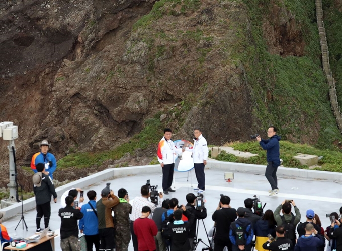 26일 오전 독도 경비대 헬기장에서 열린 제100회 전국체전 성화 채화 행사에서 김생환 서울시의회 부의장과 김병수 울릉군수가 성화를 채화하고 있다. 독도=연합뉴스.