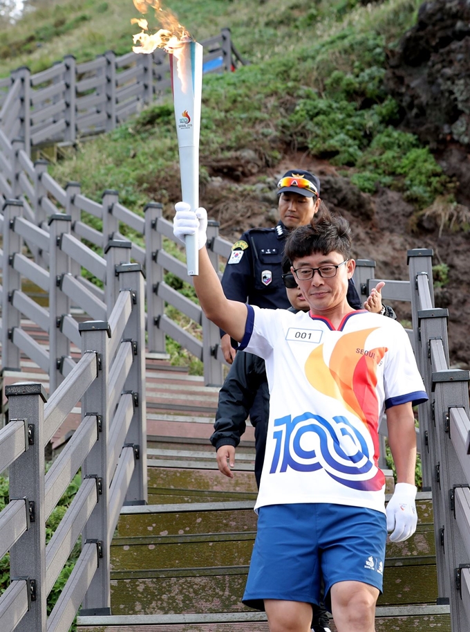 26일 오전 독도 경비대 헬기장에서 열린 제100회 전국체전 성화 채화 행사에서 허원석 독도 경비대장이 성화를 봉송하고 있다. 독도=연합뉴스.