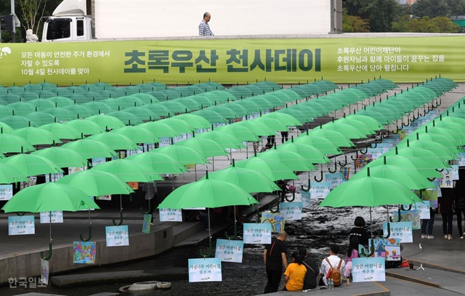 초록우산어린이재단이 오는 4일 '천사(1004)데이'를 앞두고 서울 청계천에 설치한 1004개의 초록우산 밑에서 1일 관광객들이 청계천을 즐기고 있다. 천사데이는 아동주거환경을 보장하고 아동이 안전한 환경에서 지낼 수 있도록 기부문화를 확대하기 위해 마련됐다. 홍인기 기자