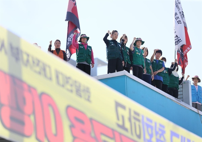 지난달 13일 경기 성남시 경부고속도로 서울요금소 캐노피에서 직접고용을 요구하며 고공농성 중인 해고 요금수납원들이 구호를 외치고 있다. 연합뉴스