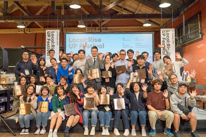 12일 전북 군산시 영화동에서 열린 '로컬라이즈 UP 페스티벌'에 참가한 23개 벤처기업인들이 현판을 전달 받고 환하게 웃고 있다. SK E&S 제공