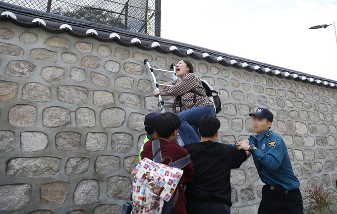 한국대학생진보연합이 18일 오후 서울 중구 주한 미국대사관저에서 방위비분담금 협상 관련 기습 농성을 하기 위해 담벼락을 넘고 있다. 뉴시스