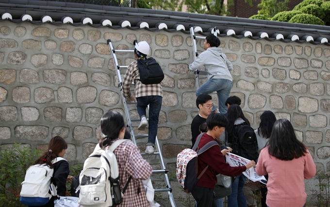 한국대학생진보연합이 18일 오후 서울 중구 주한 미국대사관저에서 방위비분담금 협상 관련 기습 농성을 하기 위해 담벼락을 넘고 있다. 뉴시스