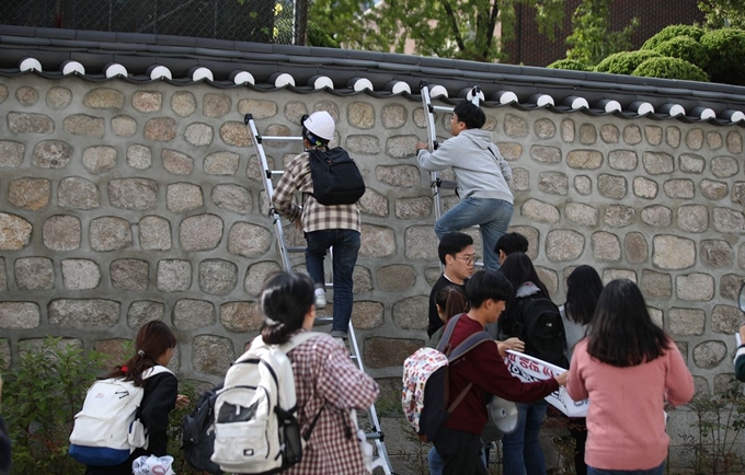 국대학생진보연합이 18일 오후 서울 중구 주한 미국대사관저에서 방위비분담금 협상 관련 기습 농성을 하기 위해 담벼락을 넘고 있다. 뉴시스