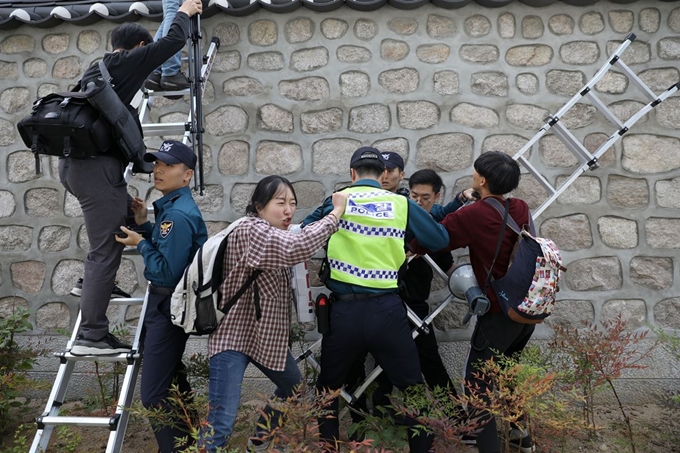 한국대학생진보연합이 18일 서울 중구 주한 미국대사관저 앞에서 방위비 분담금 인상 반대 시위를 벌이다 기습적으로 담벼락을 넘고 있다. 뉴시스