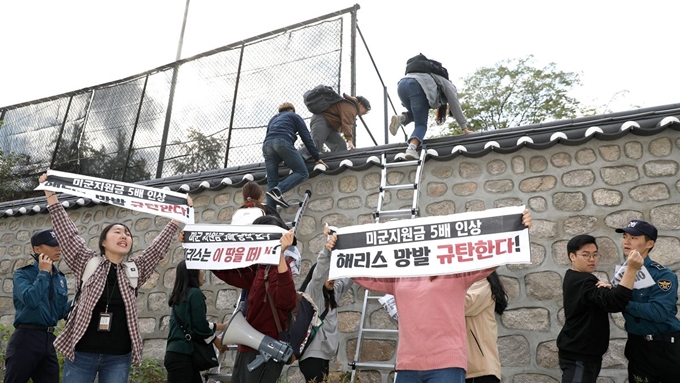 한국대학생진보연합 소속 대학생이 18일 오후 서울 중구 주한 미국대사관저에서 방위비분담금 협상 관련 기습 농성을 하기 위해 대사관저 벽을 넘고 있다. 뉴시스