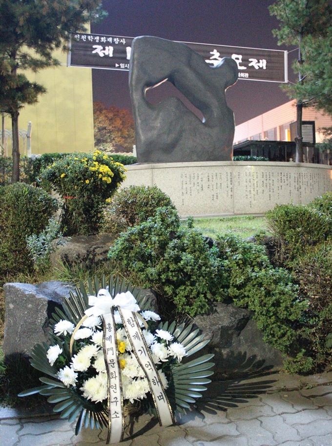 26일 오후 인천 중구 인천학생교육문화회관 야외주차장 한쪽에 서있는 ‘인현동 화재 참사 위령비’ 앞에 조화가 놓여져 있다. 인현동화재참사20주기추모준비위원회 제공