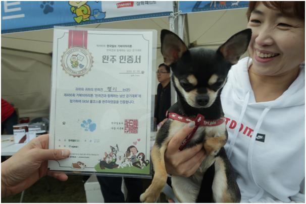 26일 서울 남산 백범광장~북측순환로 구간에서 진행된 한국일보 거북이마라톤 ‘반려견과 함께 하는 남산 걷기대회’참가자가 반려견 ‘젤리’의 발바닥 페인팅이 새겨진 완주 인증서를 보고 웃고 있다. 동그람이 이주희