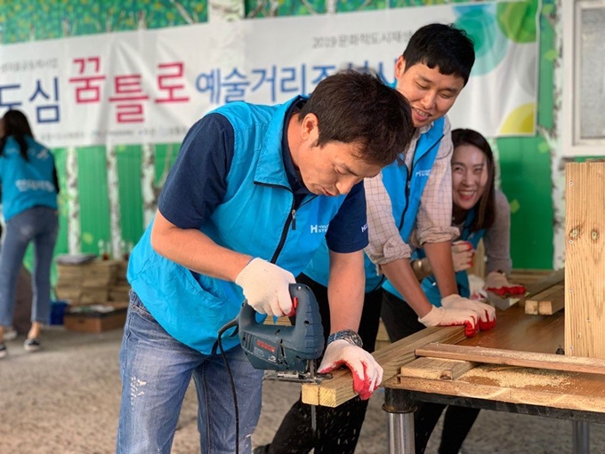 현대제철 경북 포항공장 직원들로 구성된 '온철봉사단' 회원들이 침체된 포항시 북구 여천동의 구도심을 정비하기 위해 거리 곳곳에 놓을 목재 화분을 만들고 있다. ㈜문화밥 제공