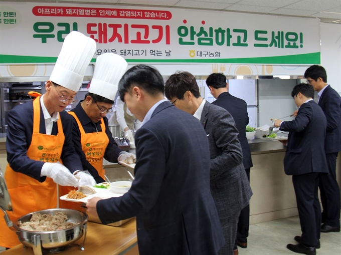 농협대구본부 직원들이 5일 수성구 중동 대구본부 구내식당에서 돼지고기 가격 하락으로 어려움을 겪고 있는 양돈농가를 돕기 위해 소비촉진 캠페인에 참여하고 있다. 농협대구본부 제공