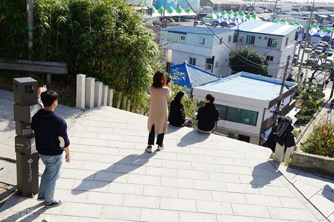 경북 포항시 남구 구룡포읍을 찾은 관광객들이 6일 KBS 수목드라마 '동백꽃 필 무렵' 촬영지인 일본인 가옥거리의 구룡포공원에서 드라마 포스터에 나온 주인공들의 모습과 비슷한 자세를 취하며 사진을 찍고 있다. 이곳은 구룡포읍 일본인 가옥거리에서도 구룡포항과 바다, 읍내가 한눈에 내려다보여 평소에도 뛰어난 풍광으로 소문 난 곳이다. 포항시에 따르면 드라마가 인기를 끌면서 촬영지인 일본인가옥거리를 찾는 관광객도 평일 하루 약 3,000명, 주말에는 하루 6,000~7,000명이 찾을 정도로 북적이고 있다. 김정혜 기자 kjh@hankookilbo.com