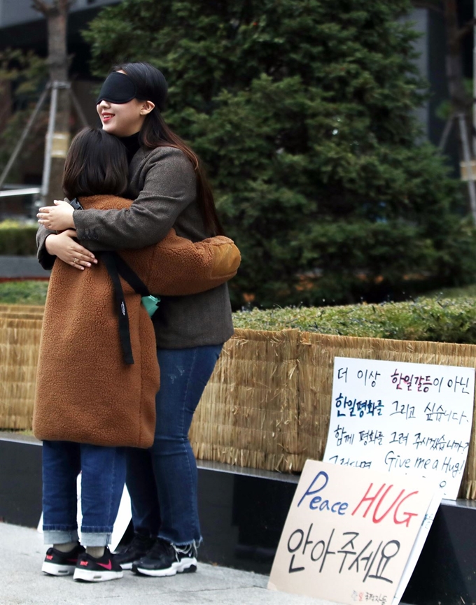 13일 오후 서울 종로구 구 일본대사관 인근에서 한 '한일국적자들' 소속 회원이 한 어린이와 프리허그를 하고 있다. 뉴시스