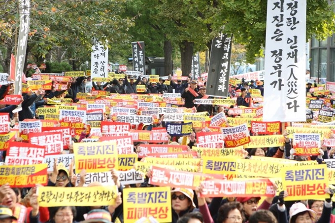 경북 포항시민들이 지난달 30일 서울 영등포구 국회 앞 도로에서 포항지진 특별법 제정 촉구 집회를 연 뒤 피해 보상을 요구하는 플래카드를 펼치며 구호를 외치고 있다. 포항 11ㆍ15촉발지진 범시민대책위원회 제공