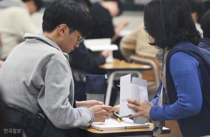 [저작권 한국일보]<2020학년도 대학수학능력시험> 감독관이 14일 오전 서울 종로구 경복고등학교에서 2020학년도 대학수학능력시험 실시 전 수험생들에게 샤프를 배부하고 있다. 박형기 인턴기자